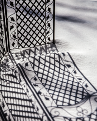An ornate iron screen casts its wintry shadow across the drifted snow.