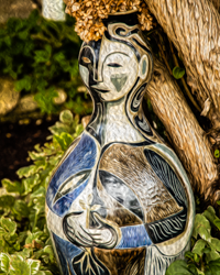 A ceramic woman with hydrangea hair rests in the summer shade.